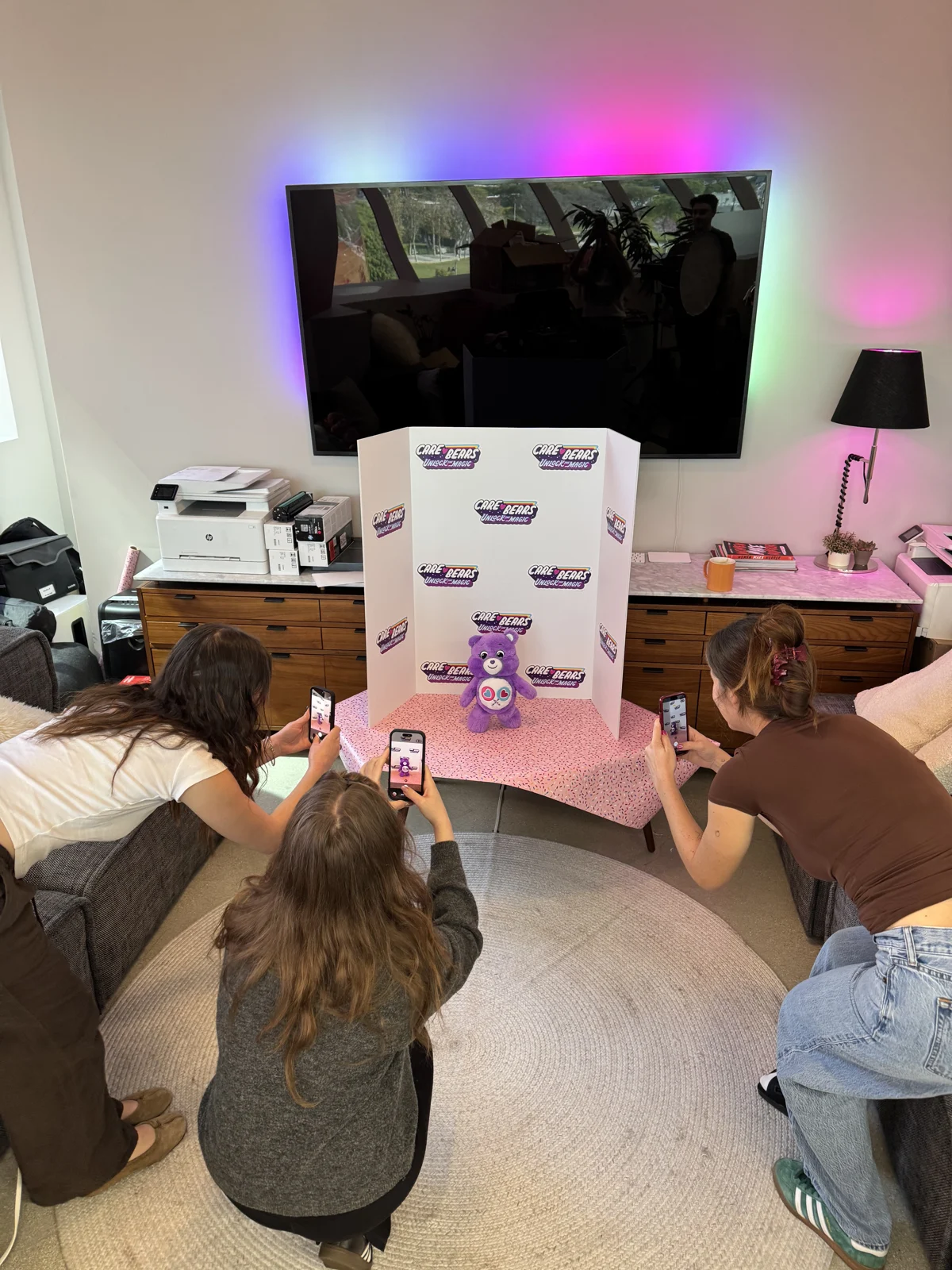 Team photographing the plush bear on a small set in the office