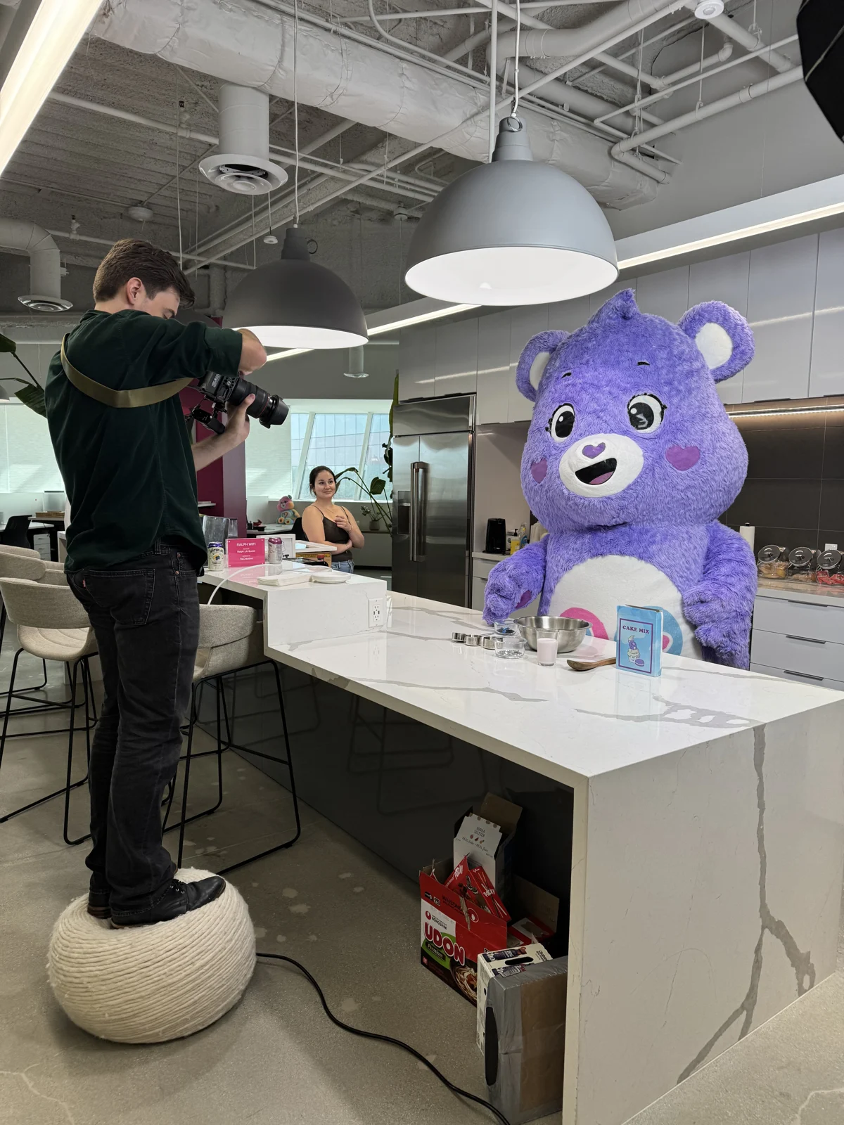 Photographer on a stool shooting a Care Bear in the office kitchen