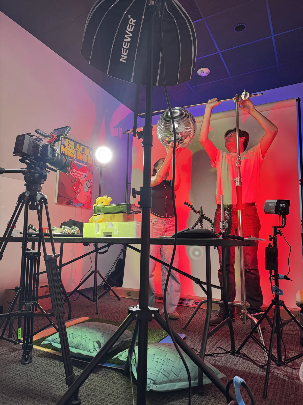 Crew rigging a disco ball over a tabletop set under red and purple light
